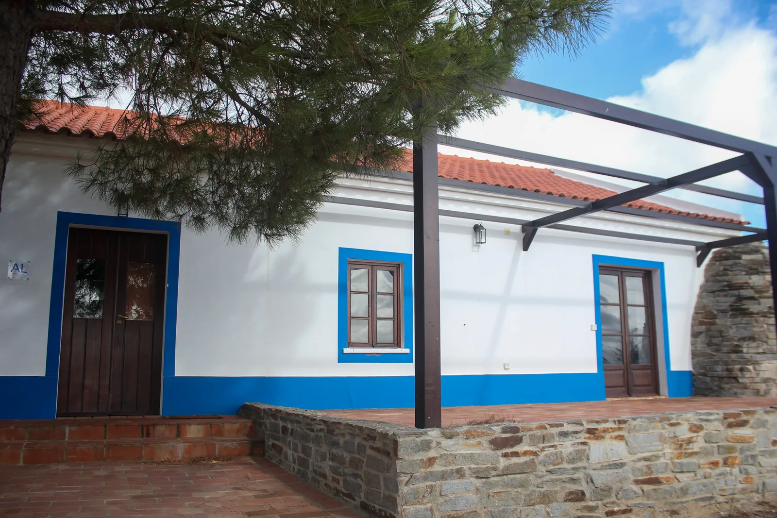 Portela Nova's whitewashed farmhouse with blue trim beneath pine trees