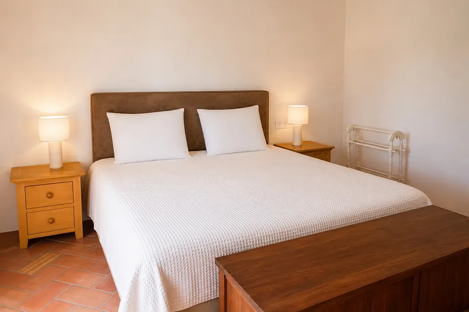 A Portela Nova guest bedroom with a double bed, white cover and bedside lamps