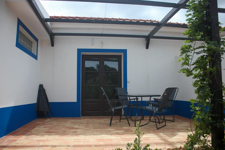 A table and chairs on the terrace outside a whitewashed Portela Nova suite
